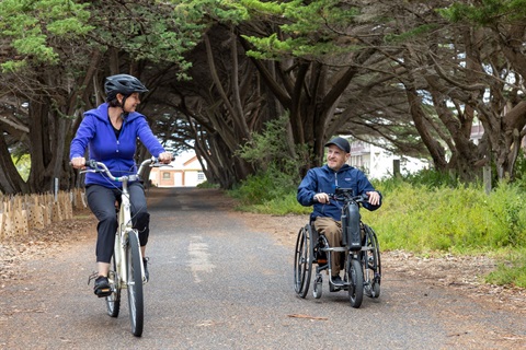 Man in wheelchair and lady on bike on path at Point nepean