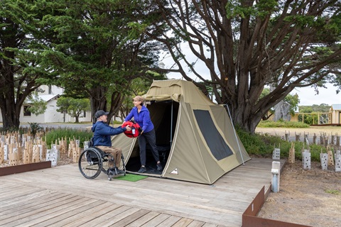 Man in wheelchair in front of tent.