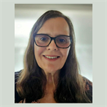 Photograph of Kim smiling, she is wearing glasses and has long brown hair