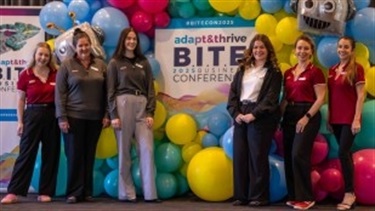 Group of attendees under the 2025 B.I.T.E Conference balloon sign
