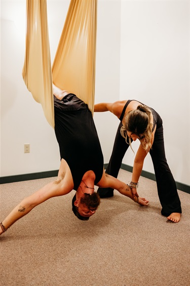 Aerial yoga student supported in inversion